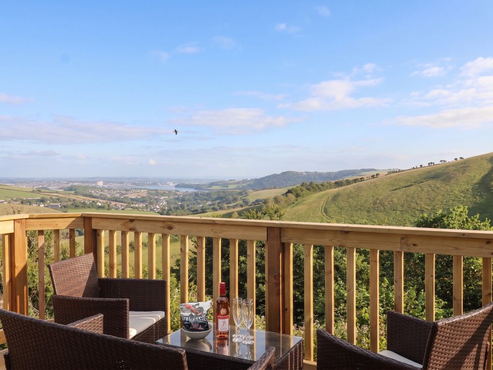 A deck with a table and chairs overlooking a valley at Lodge 19 in Torpoint