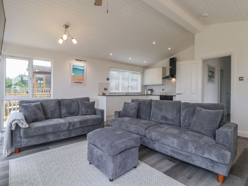 A living room with sofas and a kitchen area at Lodge 19 in Torpoint