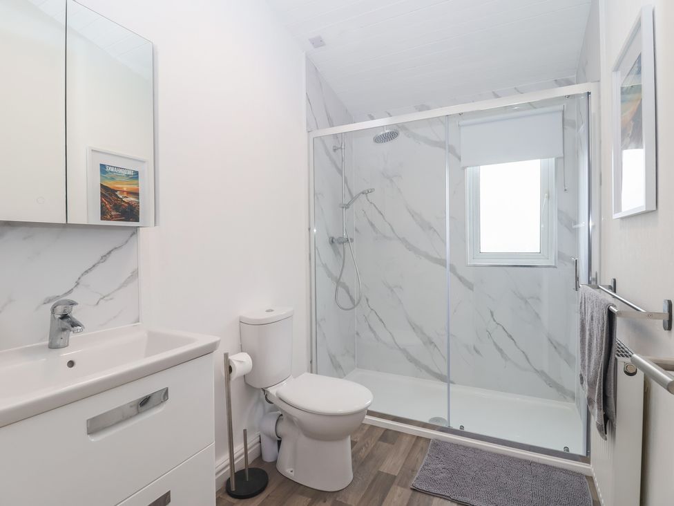 A bathroom with a sink, shower, and towel rail at Lodge 19 in Torpoint