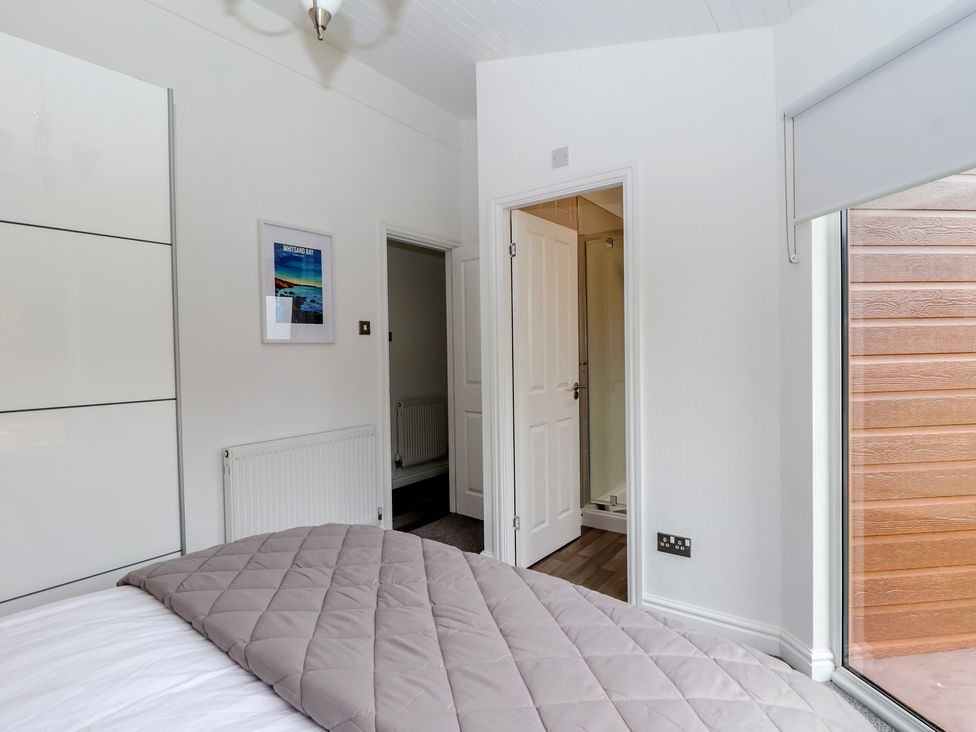 A bedroom with a bed and a door leading to a bathroom at Lodge 19 in Torpoint