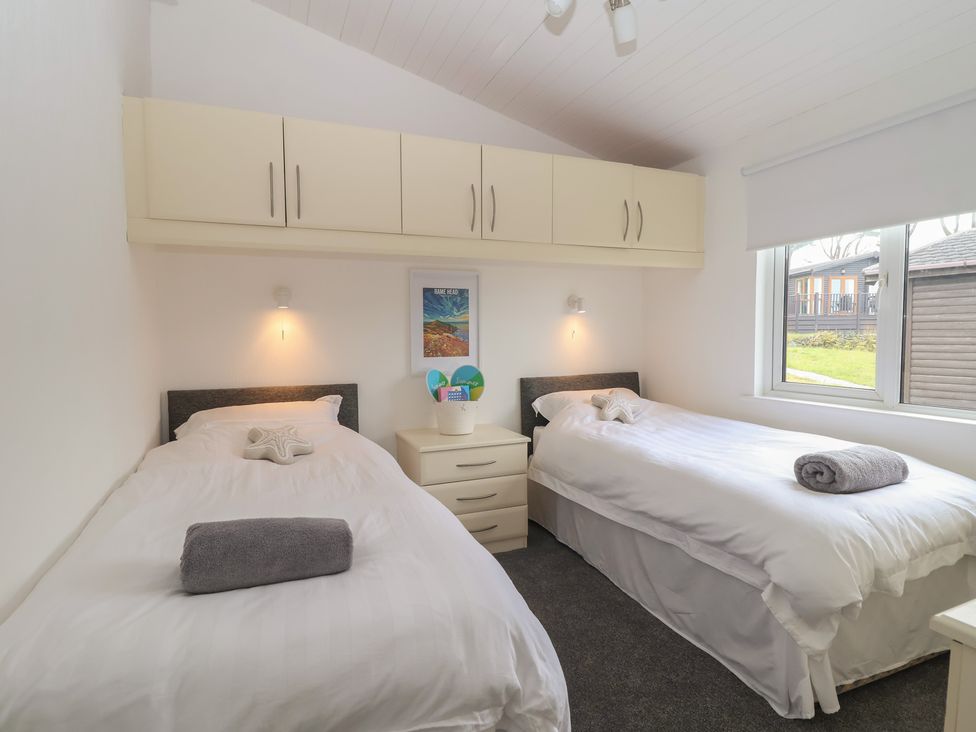 A bedroom with twin beds and a window at Lodge 19 in Torpoint