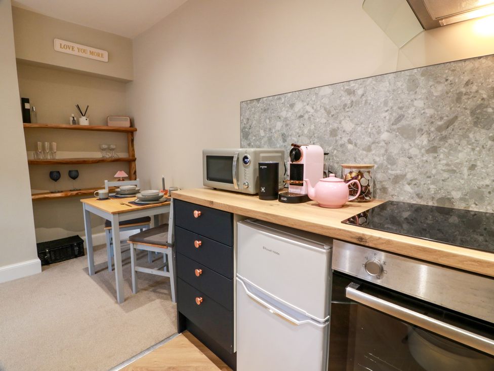 A kitchen with refrigerator, stove, microwave, and table at 19 Biggiesknowe Peebles