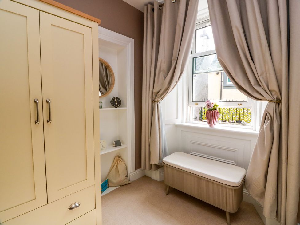 A bedroom with a wardrobe, mirror, and window at 19 Biggiesknowe Peebles