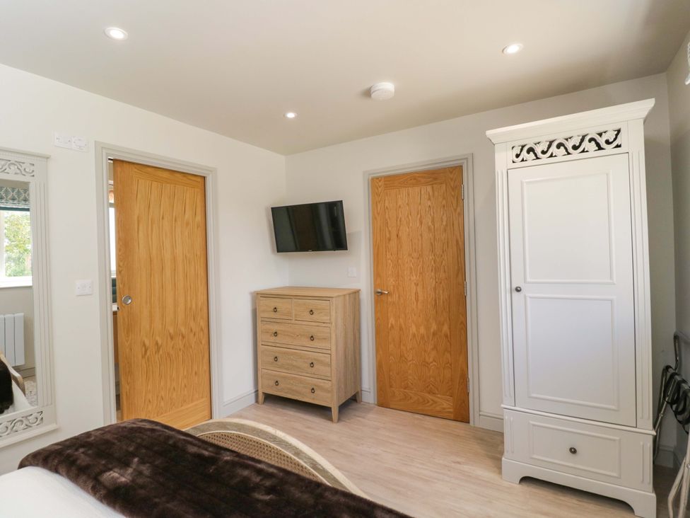 A bedroom with a television and wooden furniture at Poppy Patch in Stratton Audley near Bicester
