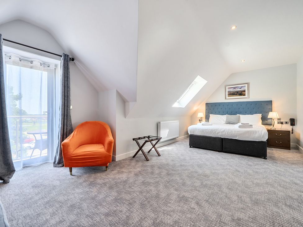 A bedroom with a bed, armchair and bedside tables at Cotswolds Apartments 4B/S8, Chipping Norton