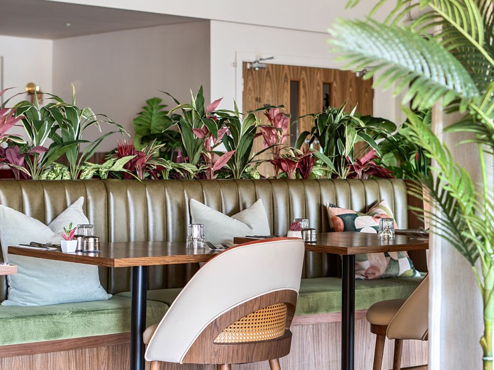A dining room with booth seating and plants at Cotswolds Apartments 4B/S8 in Chipping Norton