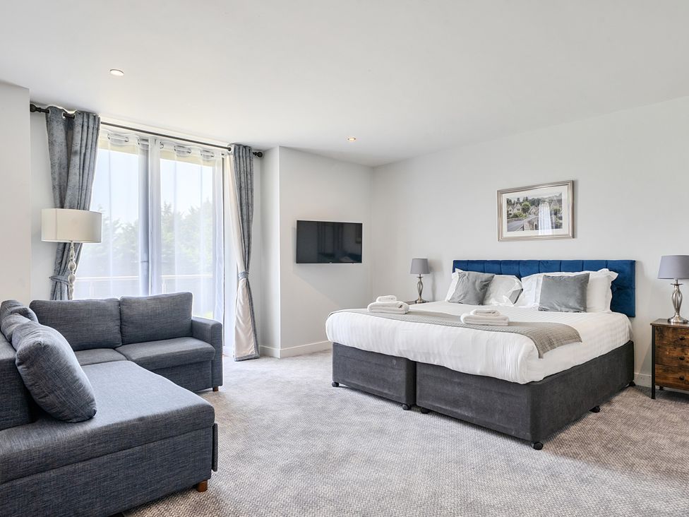 A bedroom with a king size bed and a sofa at Cotswolds Apartments 4B/S8 in Chipping Norton