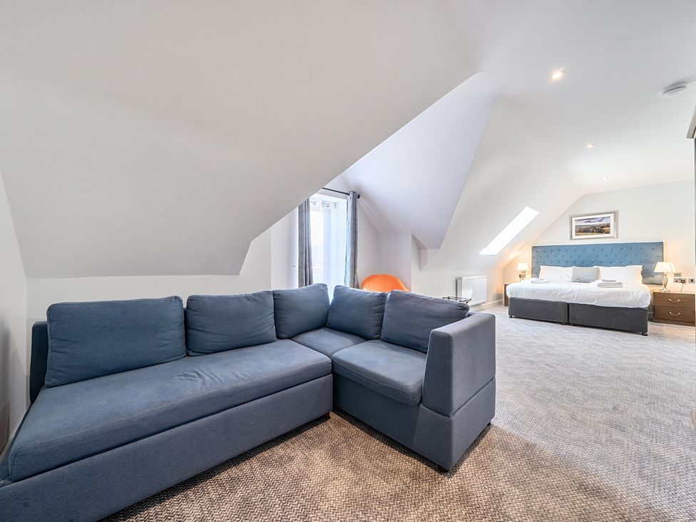 A bedroom with a blue sofa and a bed at Cotswolds Apartments 4B/S8 in Chipping Norton