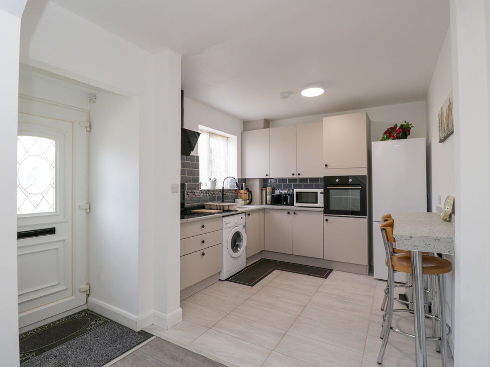 A kitchen with appliances and barstools at 167 Leybourne Avenue Bournemouth