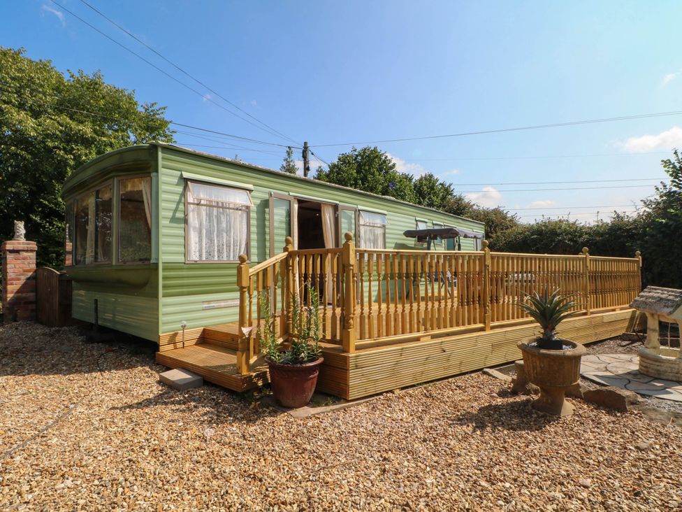 A caravan with a wooden deck at Buzzards Retreat in Wrexham