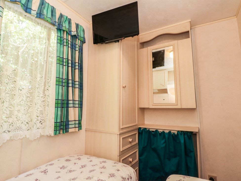A bedroom with a bed, wardrobe and television at Buzzards Retreat in Wrexham