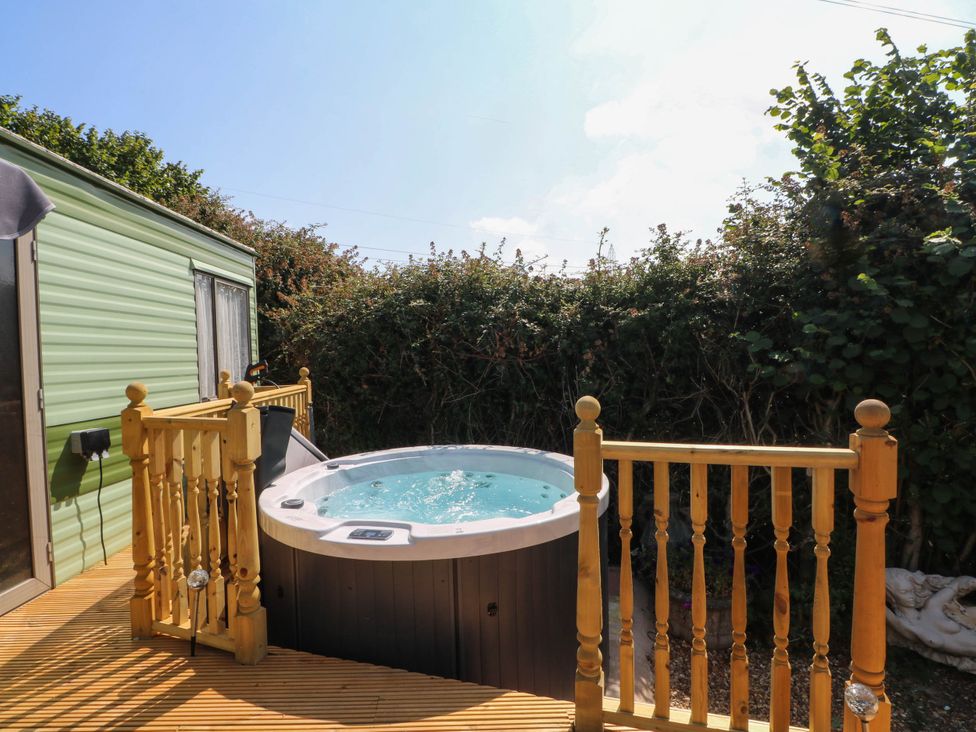 An outdoor area with a hot tub and wooden decking at Buzzards Retreat in Wrexham
