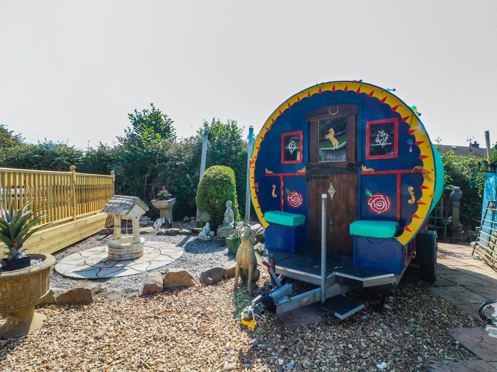A garden with a caravan, stone path, and decorative objects at Buzzards Retreat in Wrexham