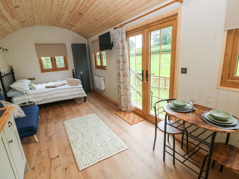 A bedroom with a bed, table and chairs at Shepherd Hut 1 Llandeilo