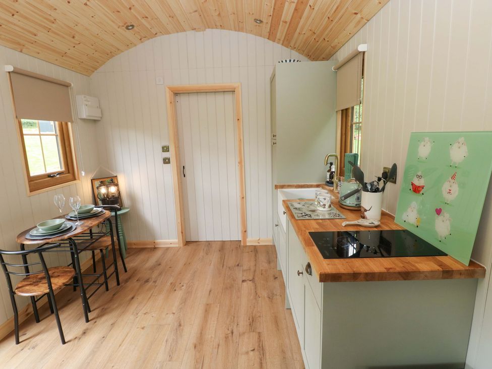 A kitchen with dining table and chairs at Shepherd Hut 1 in Llandeilo