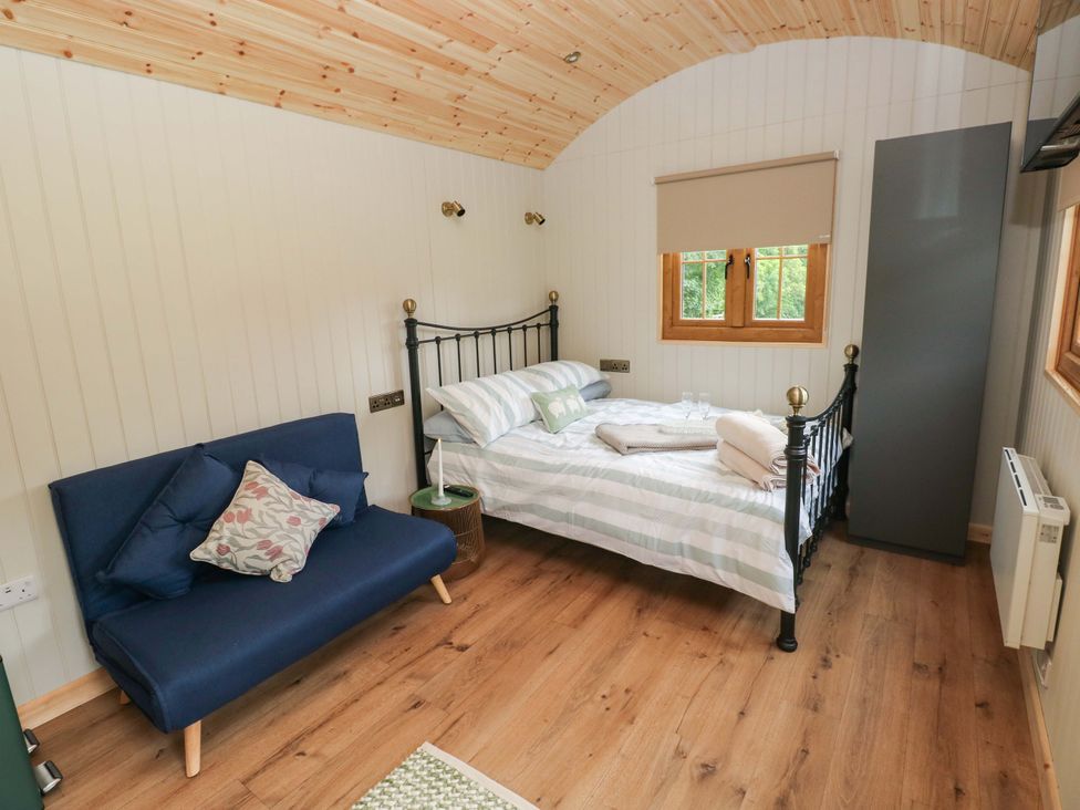 A bedroom with a bed and a sofa at Shepherd Hut 1 in Llandeilo