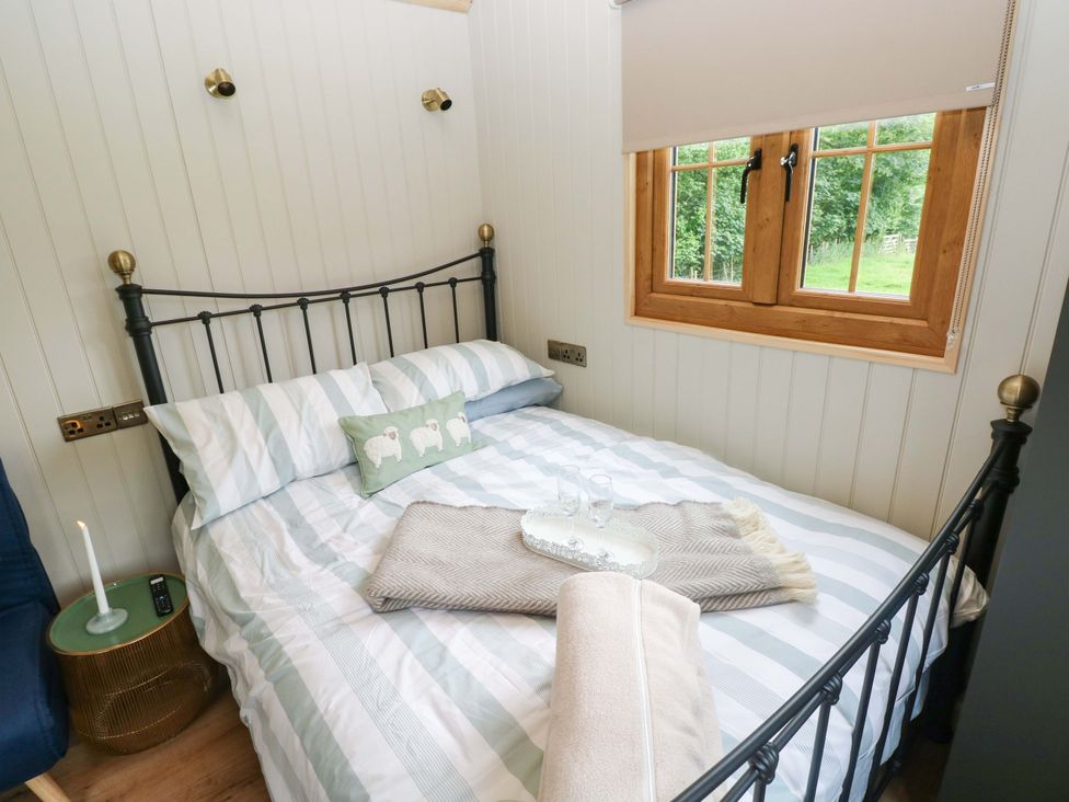 A bedroom with a bed and a window at Shepherd Hut 1 in Llandeilo