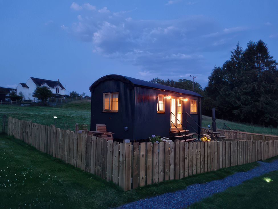 A shepherd's hut with a wooden fence and pathway at Cwtch 1 Near Llandeilo