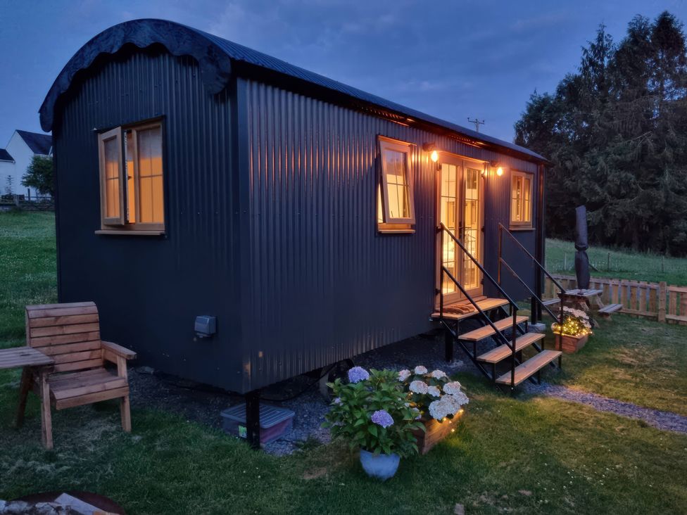 A shepherd's hut with garden chair and pathway at Cwtch 1 Near Llandeilo