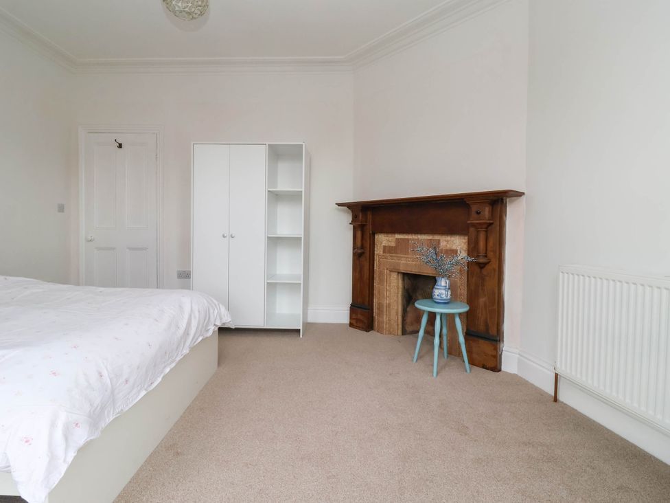 A bedroom with a bed, wardrobe, fireplace and a small table at 154 Queen Street Withernsea