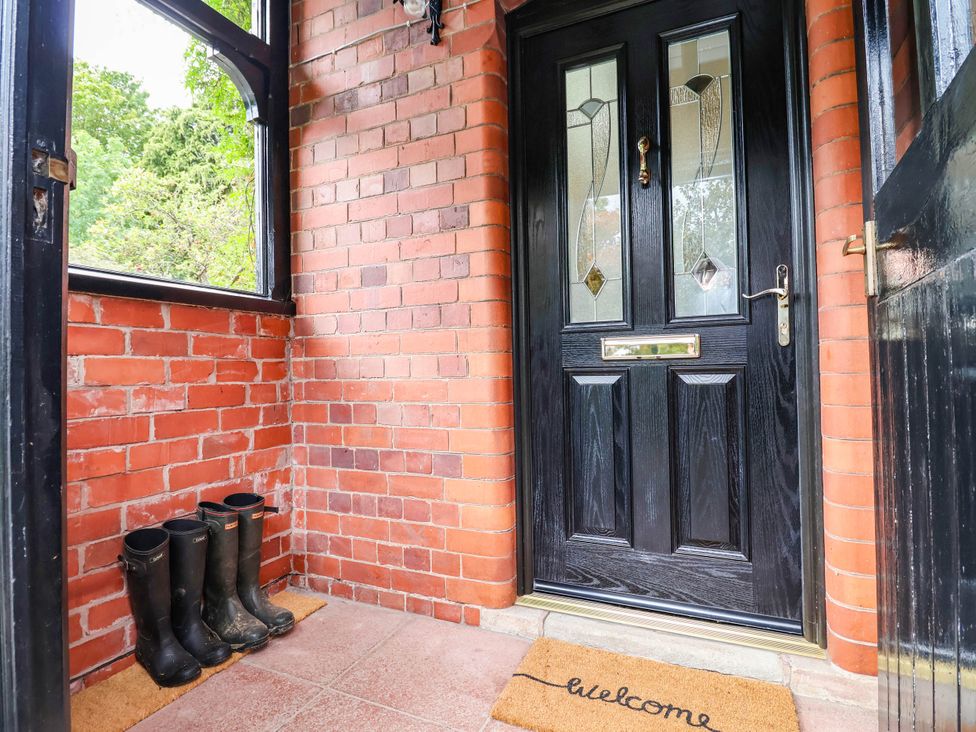 An entryway with a black front door and rubber boots at Lyneal Cottage Ellesmere