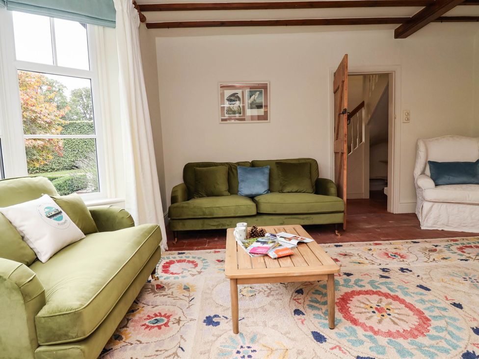 A living room with green sofas and a coffee table at Lyneal Cottage in Ellesmere