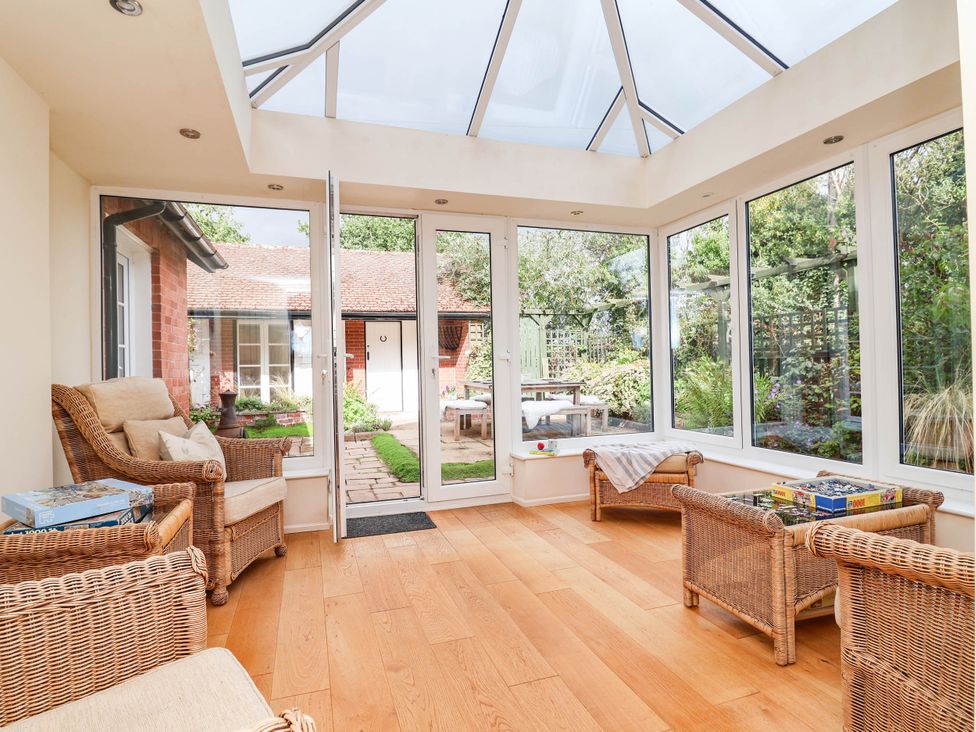 A conservatory with seating and a view of the garden at Lyneal Cottage in Ellesmere