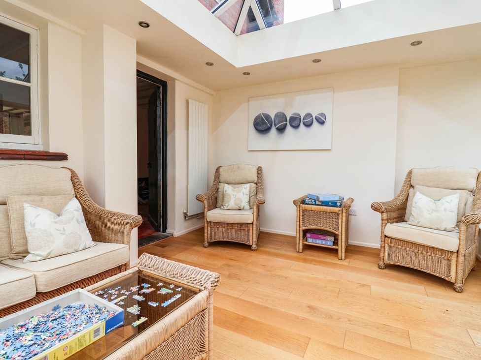 A conservatory with rattan chairs and a coffee table at Lyneal Cottage Ellesmere