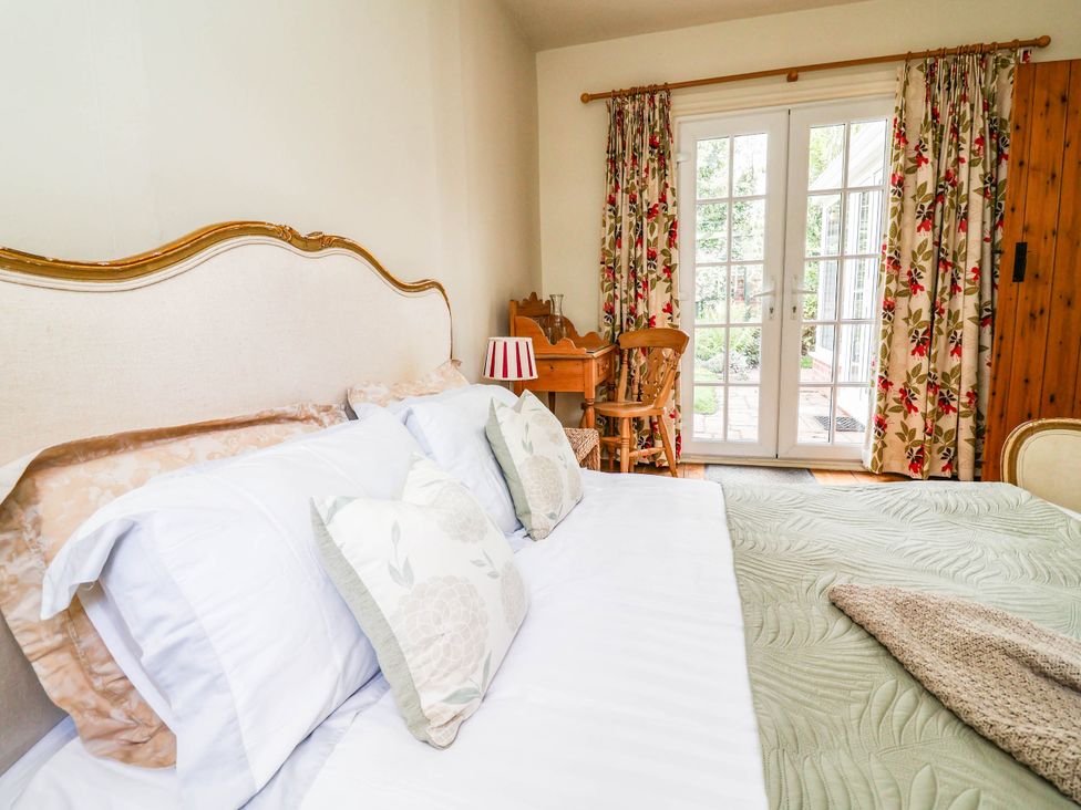 A bedroom with two beds and a desk at Lyneal Cottage in Ellesmere