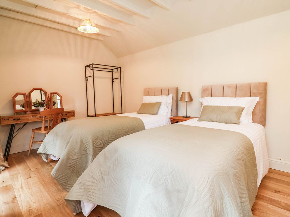A bedroom with two beds and a desk at Lyneal Cottage in Ellesmere