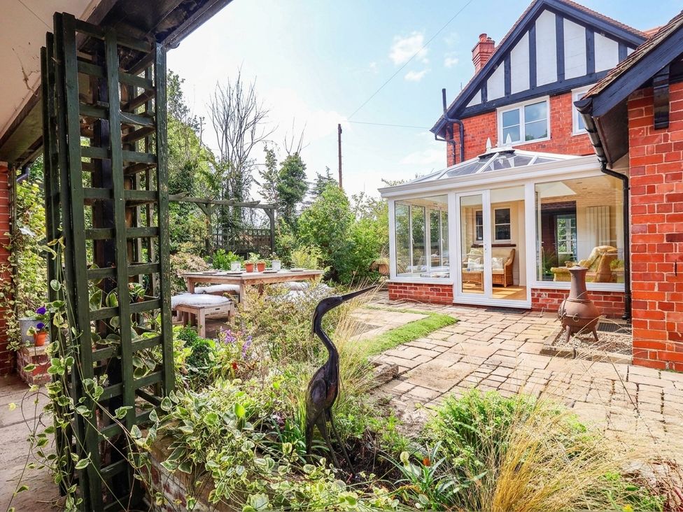 A garden with a conservatory and seating area at Lyneal Cottage Ellesmere