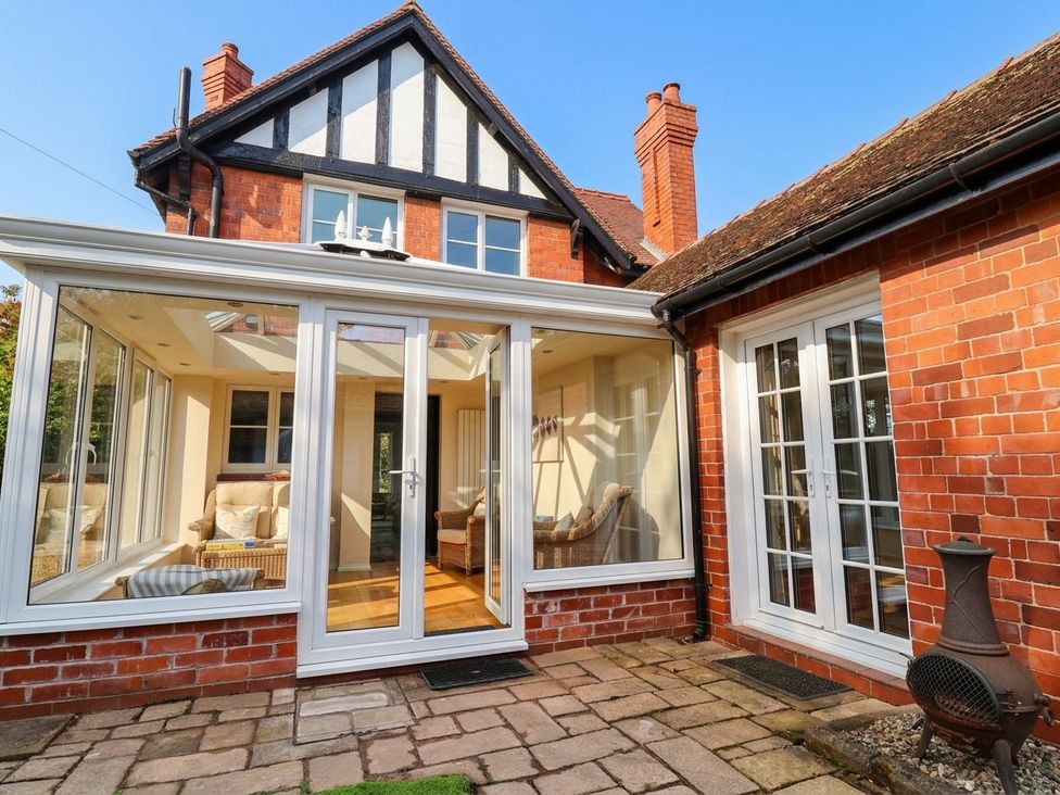A conservatory with sofa and coffee table at Lyneal Cottage in Ellesmere