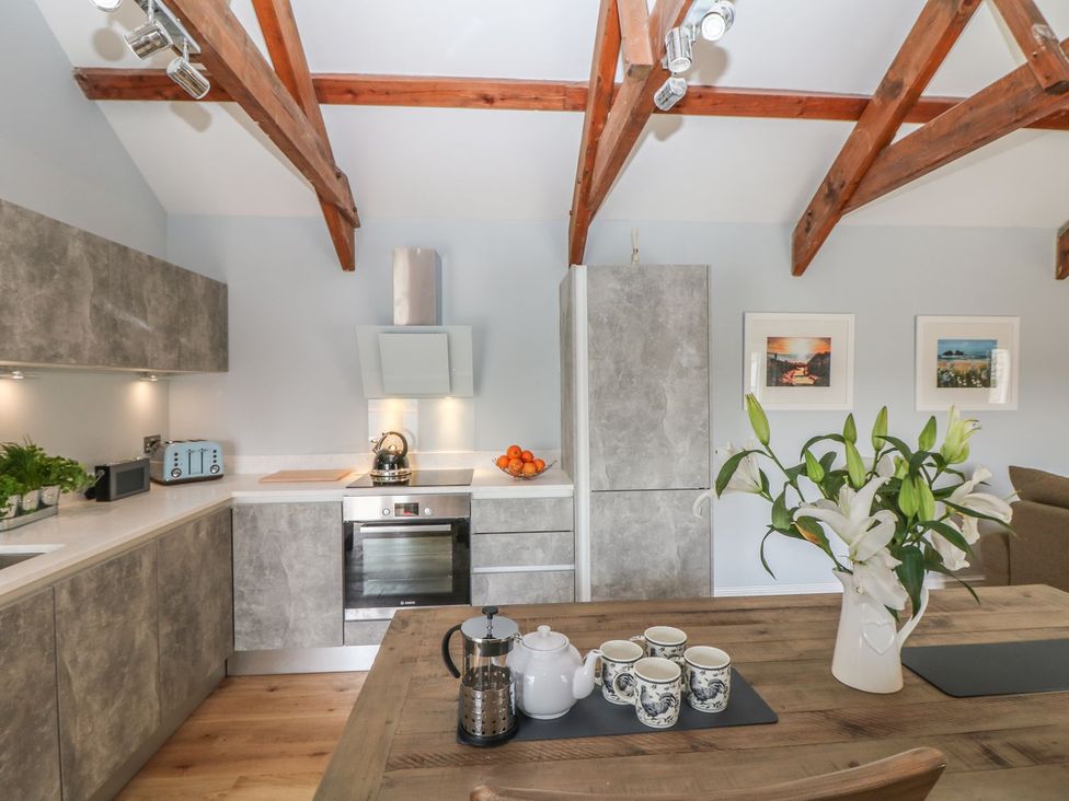 A kitchen with a dining table and floral arrangement at Helford in Treverva near Constantine