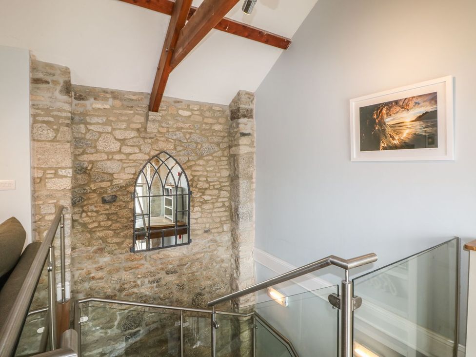 A staircase with a stone wall and a mirror at Helford in Treverva near Constantine