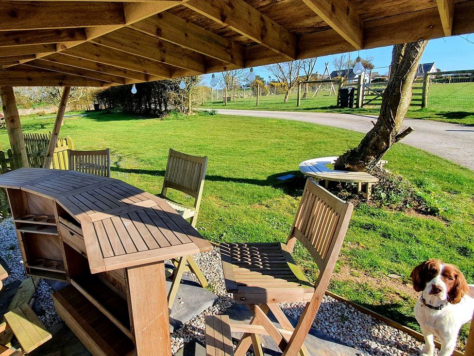 A garden with a wooden table and chairs at Helford in Treverva near Constantine