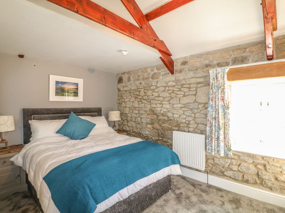 A bedroom with a bed and stone wall at Helford in Treverva near Constantine