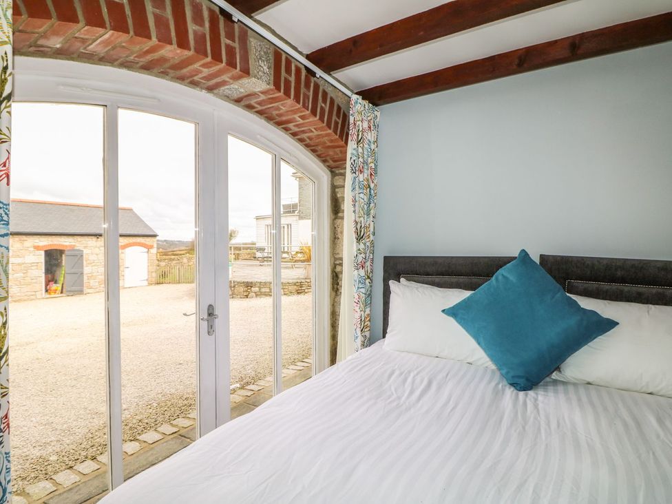 A bedroom with a bed and sliding doors at Helford in Treverva near Constantine