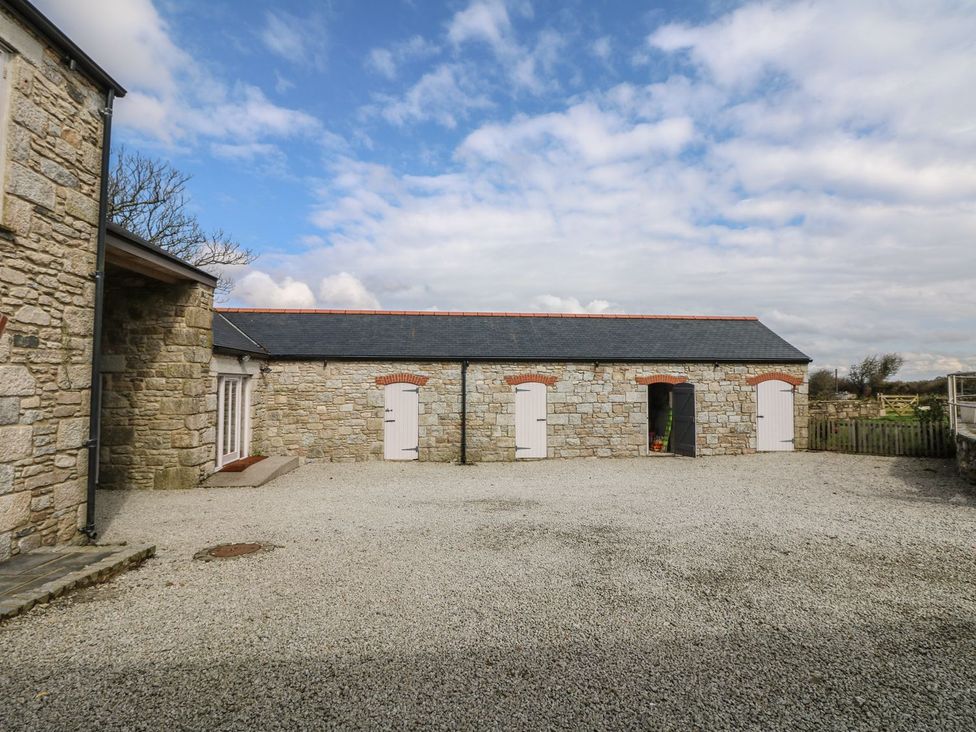 An outdoor area with a stone building and gravel surface at Helford near Treverva