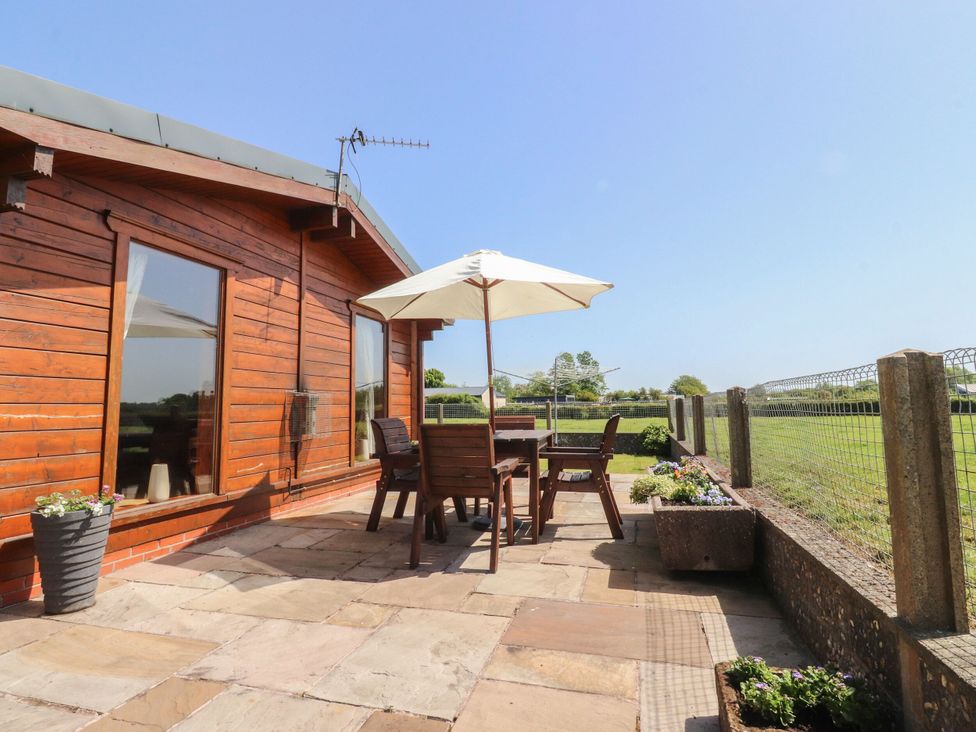 An outdoor seating area with wooden furniture and a parasol at Chestnut Lodge Pilling near Stake Pool