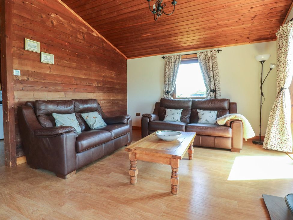 A living room with leather sofas and a wooden table at Chestnut Lodge in Pilling near Stake Pool