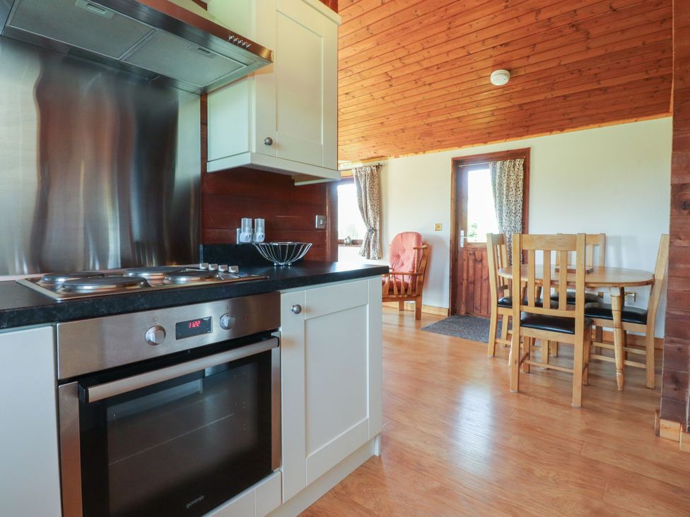 A kitchen with an oven and wooden dining table at Chestnut Lodge in Pilling near Stake Pool
