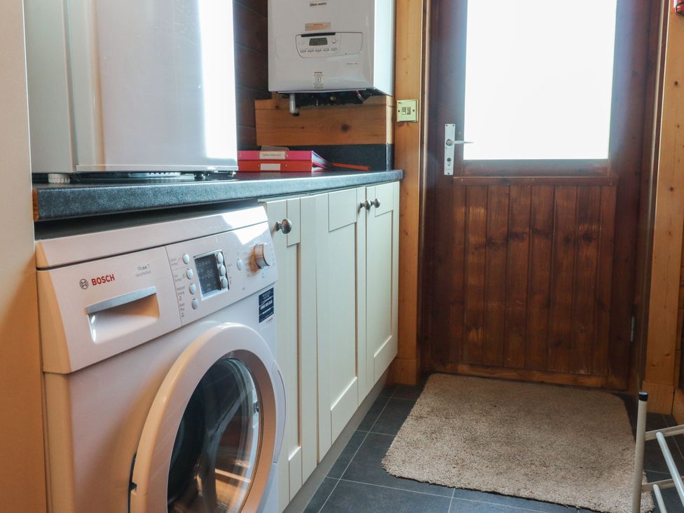 A laundry room with a washing machine and door at Chestnut Lodge in Pilling near Stake Pool
