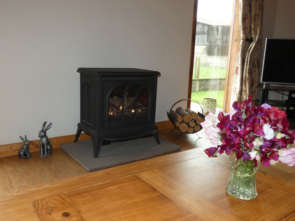 A living room with a stove, vases, and decorative rabbits at Chestnut Lodge in Pilling