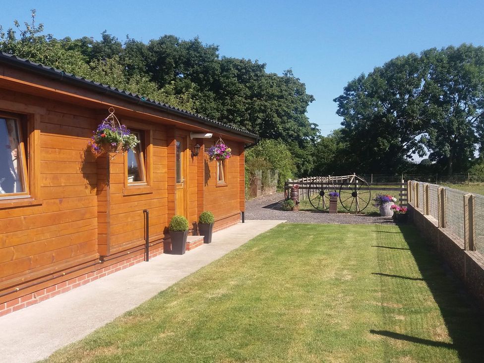 An outdoor area with a wooden cabin and flower pots at Chestnut Lodge in Pilling