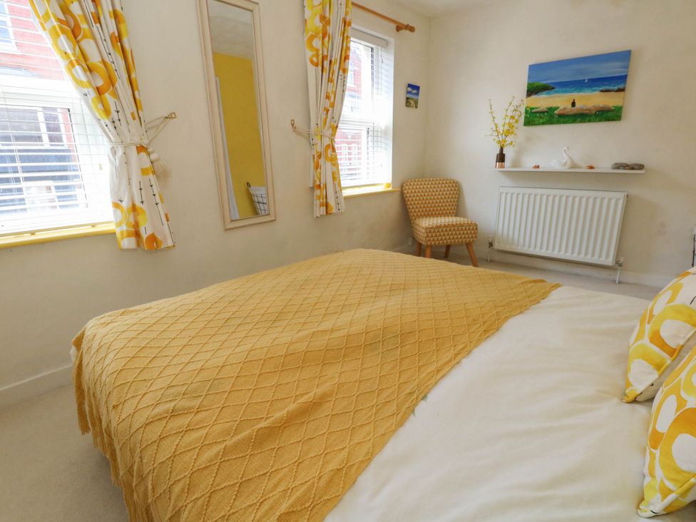 A bedroom with a bed, chair and mirror at Driftmark in Weymouth