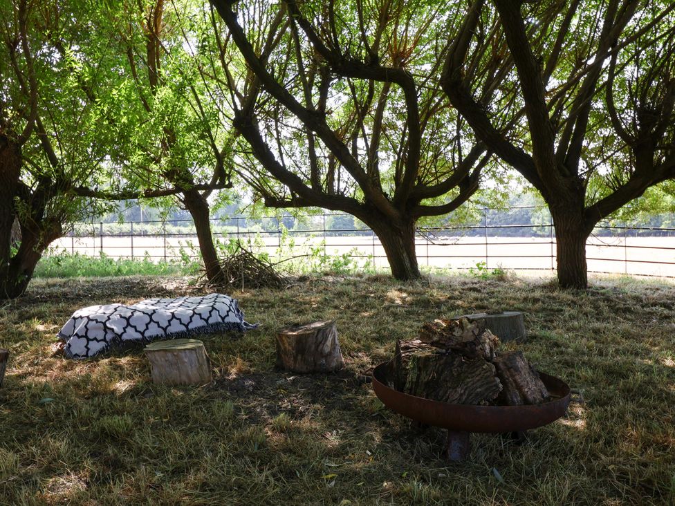 A shaded area with trees, a blanket and a fire pit at The Old Dairy Corsley near Warminster