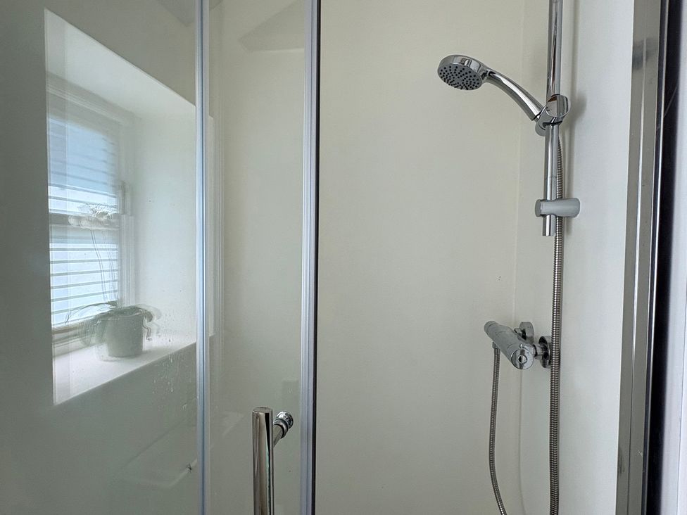 A shower with glass door and showerhead at The Old Dairy in Corsley near Warminster