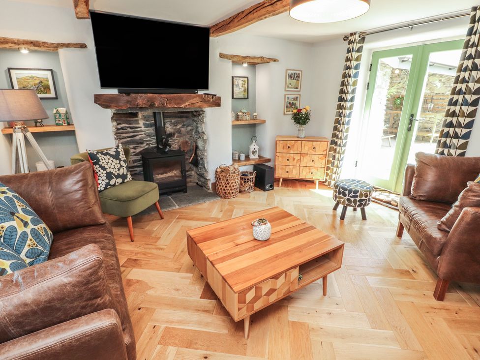 A living room with a fireplace and seating at Haws Bank Cottage in Coniston