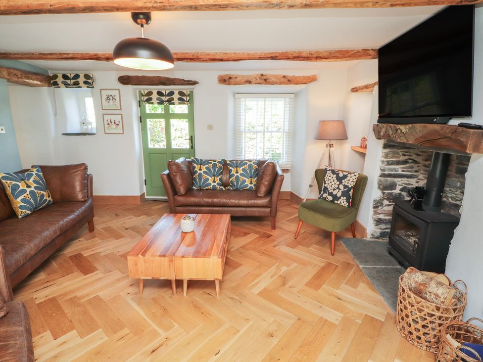 A living room with a sofa, coffee table, and fireplace at Haws Bank Cottage in Coniston