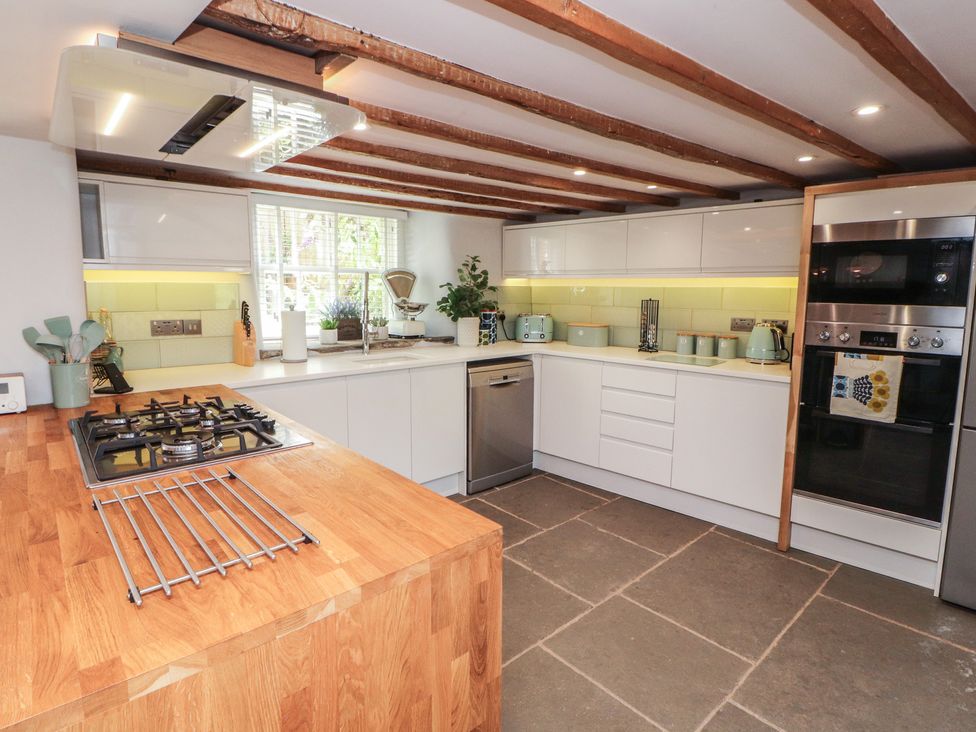A kitchen with a gas stove and white cabinetry at Haws Bank Cottage in Coniston